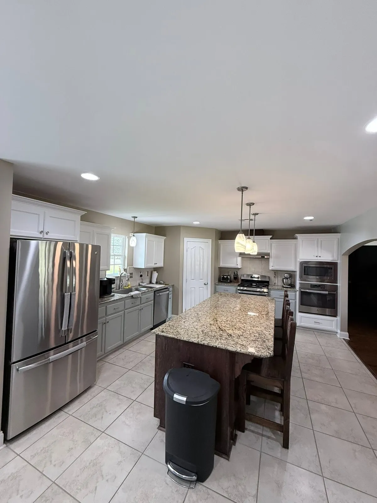 Kitchen with white and gray painted cabinets, a granite-topped island and a tile floor