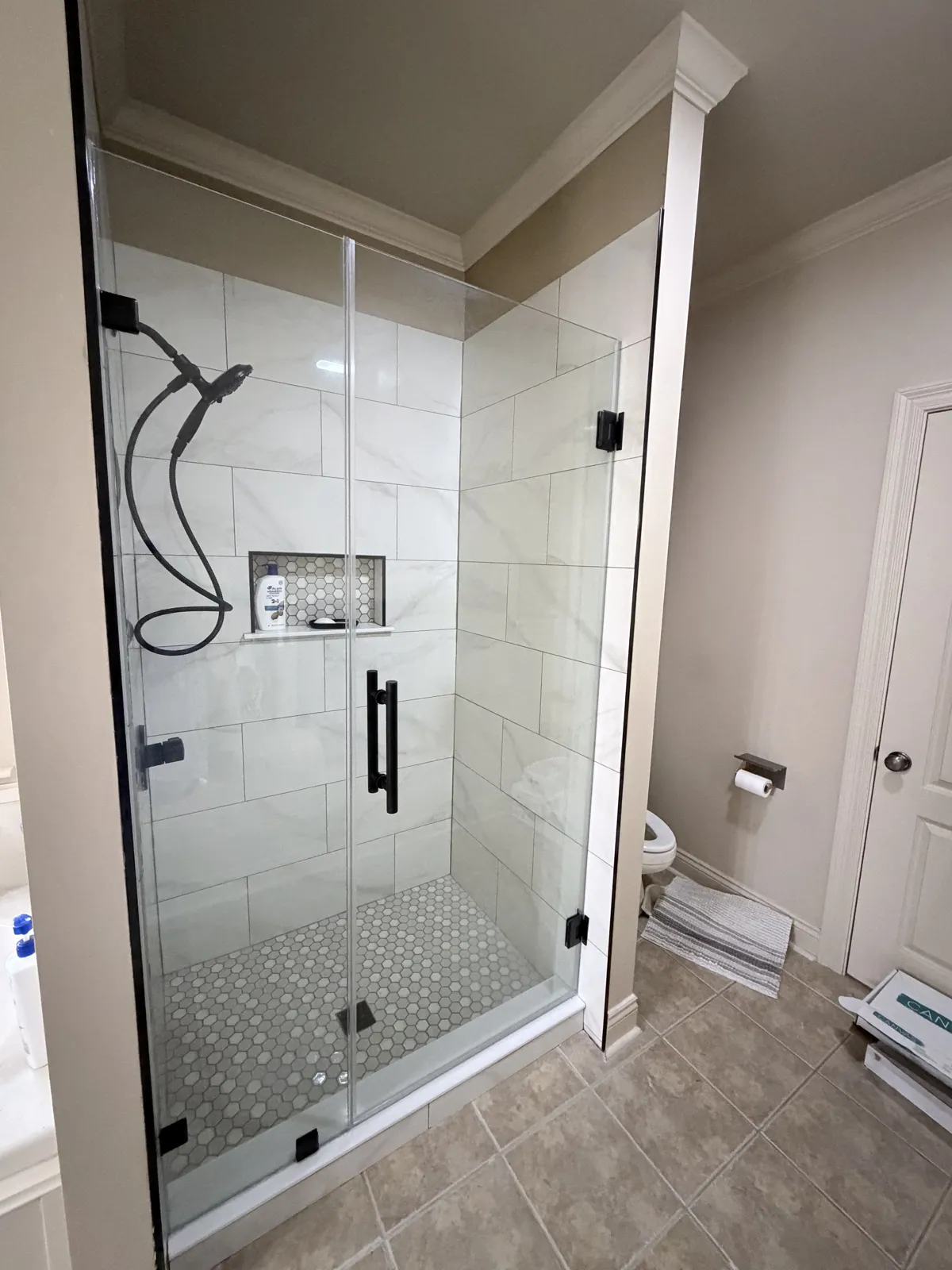 Walk-in tile shower with glass enclosure and recessed niche