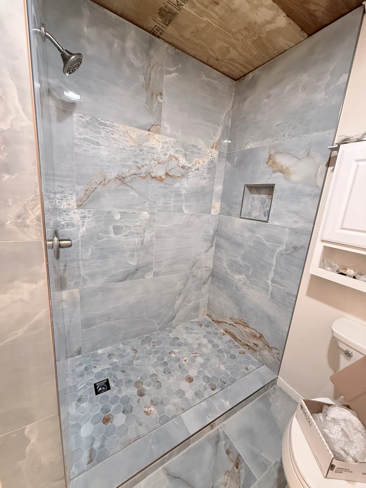Tiled shower with large-format stone-look tile and mosaic floor