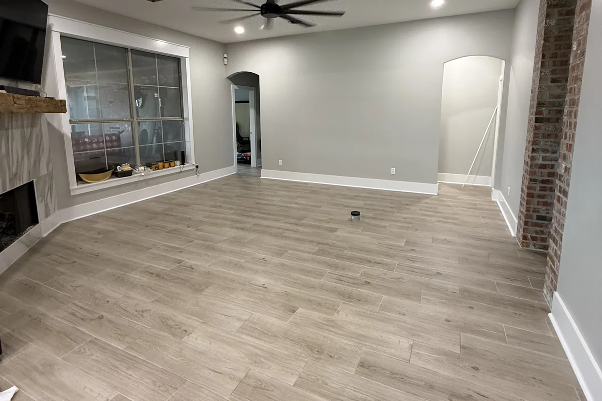Wood-look plank tile flooring installed in an open living room with a brick archway