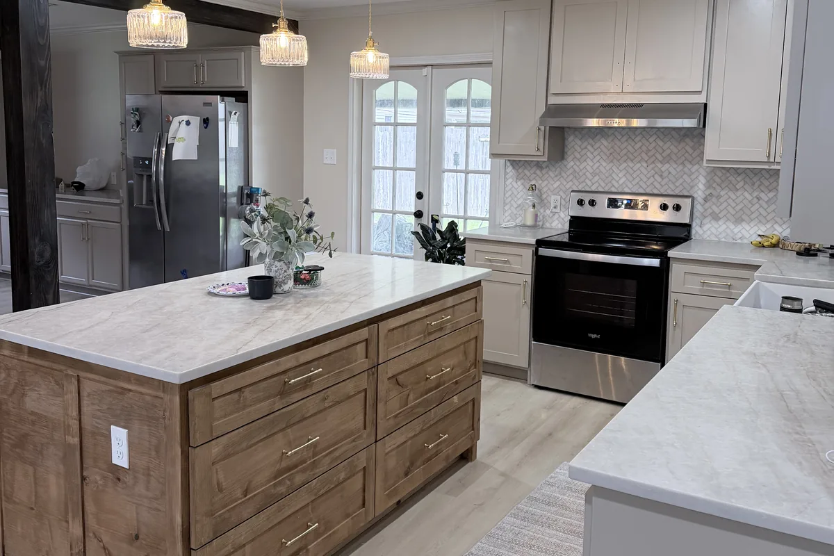 Remodeled kitchen island with stained wood drawers, brass pulls and a stone countertop
