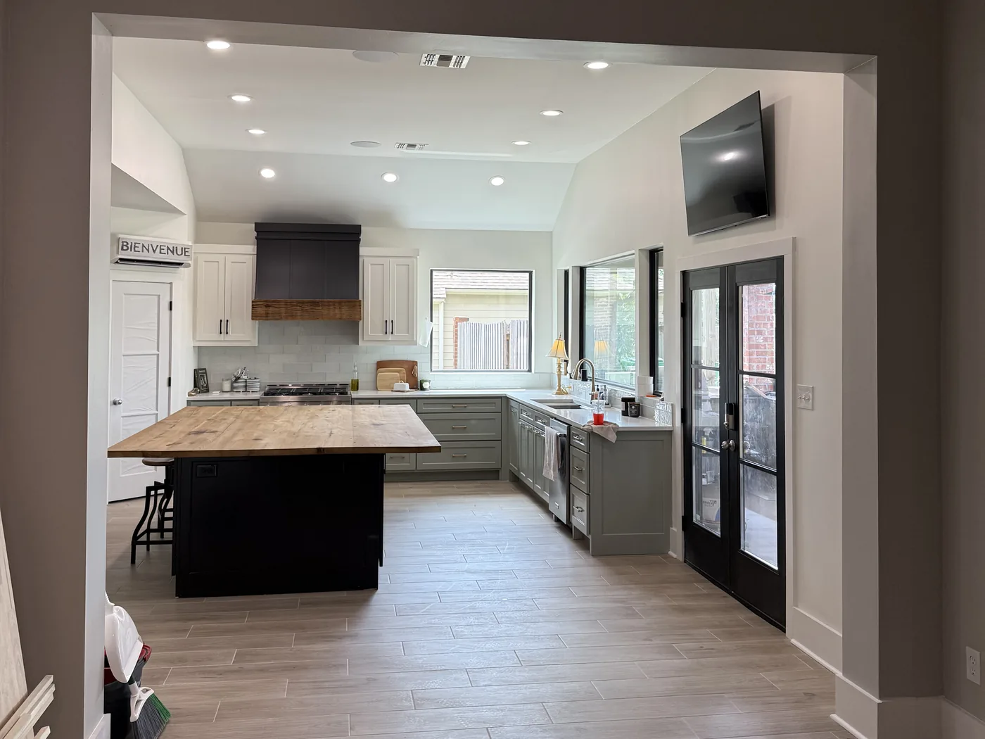 Remodeled open kitchen with a reclaimed-wood island, stained wood range hood and wood-look tile floor